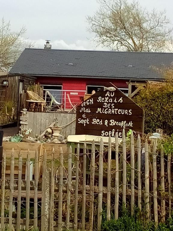 um sinal em frente a uma casa com uma cerca em Au relais des migrateurs em Le Crotoy