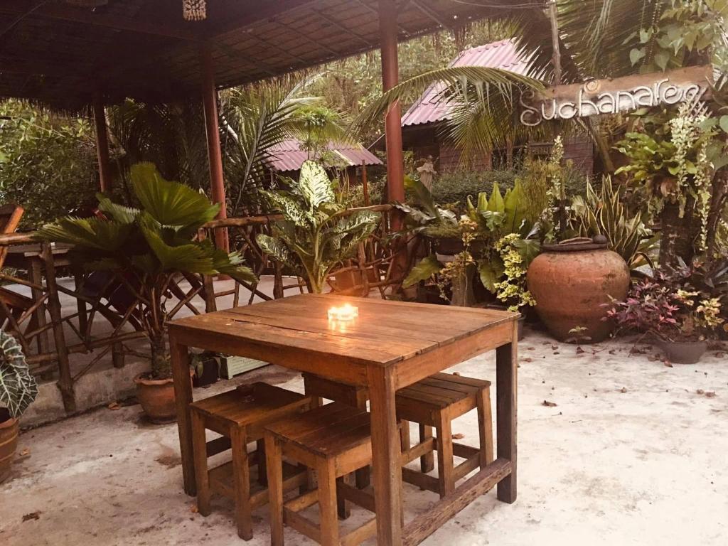 a wooden table and bench in a garden with plants at Suchanaree@Laemngop in Trat