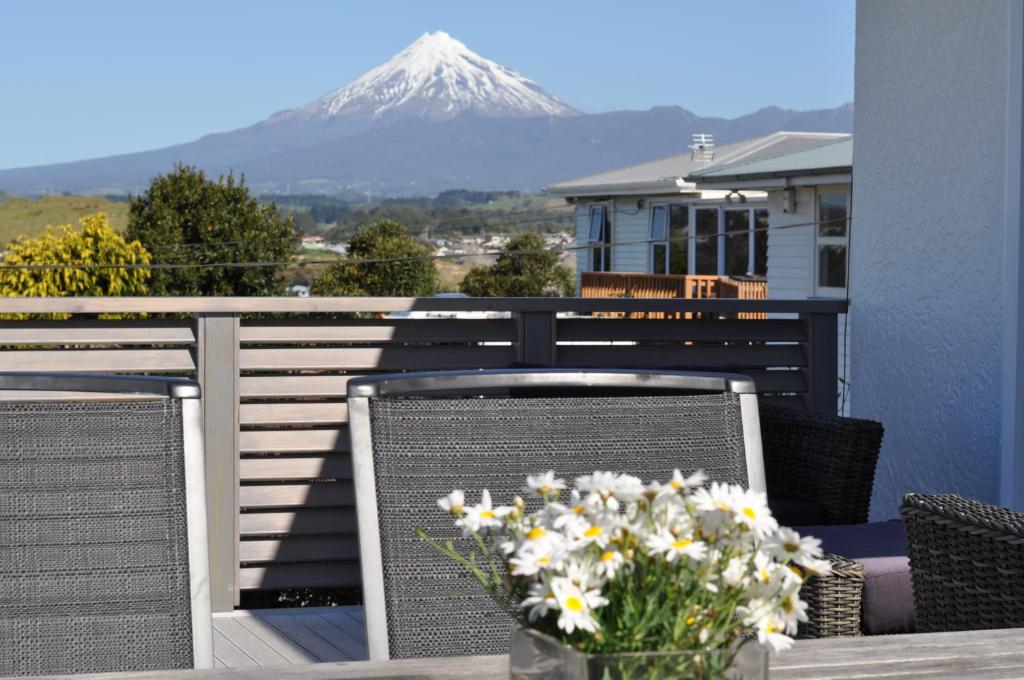 a table with flowers on a balcony with a mountain at 16 Havelock in New Plymouth