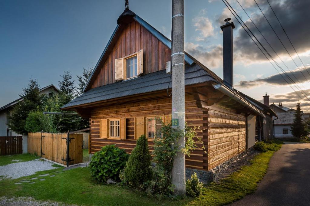 una casa de madera con un poste delante en Drevenica Polomka-BBQ-Village center-Traditional design-Close to major attractions, en Brezno