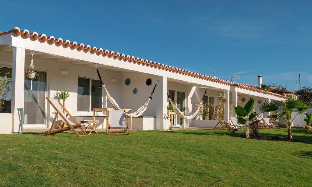 una casa con cortile attrezzato con sedie e amache di Ao Sabor do Vento (+12 ) ad Aljezur