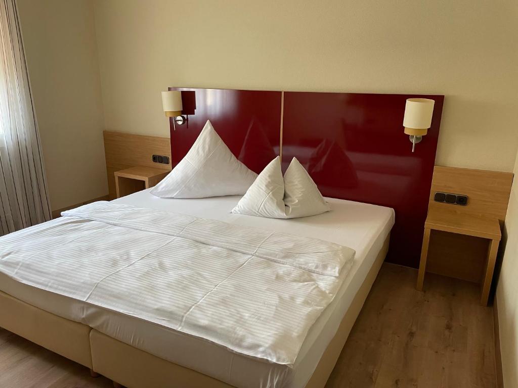 a bedroom with a large white bed with a red headboard at Hotel Paffhausen in Wirges