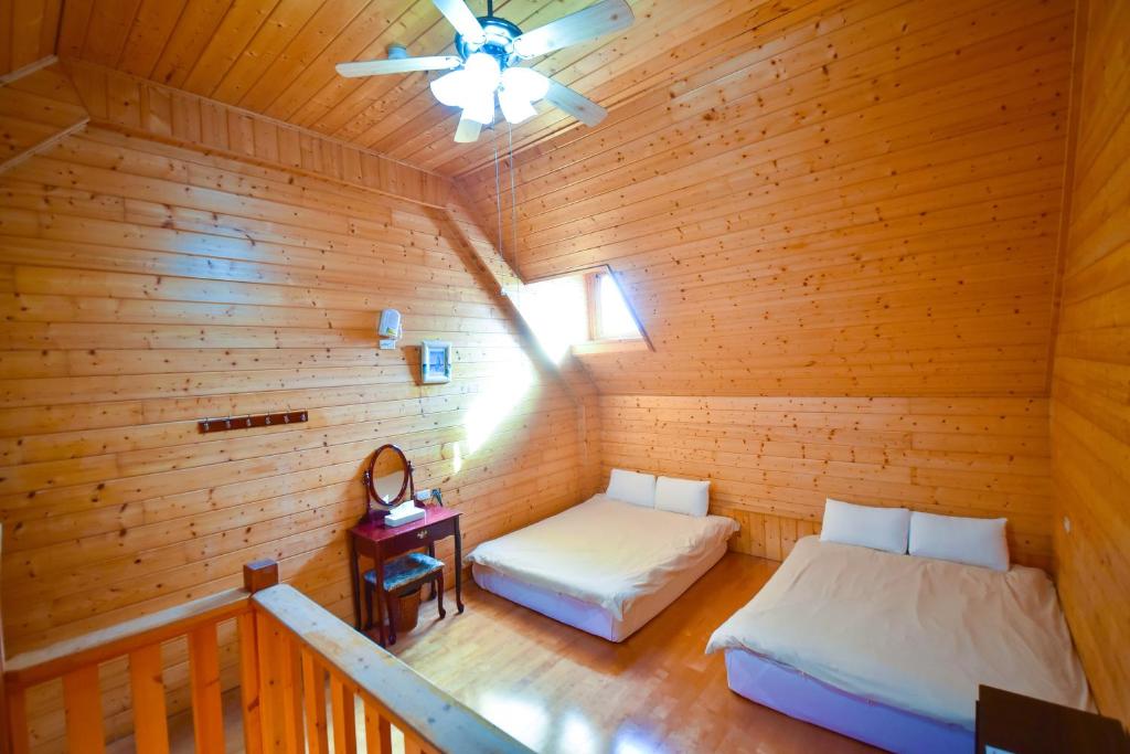 an attic room with two beds and a ceiling fan at Beverly B&amp;B in Ren&#39;ai