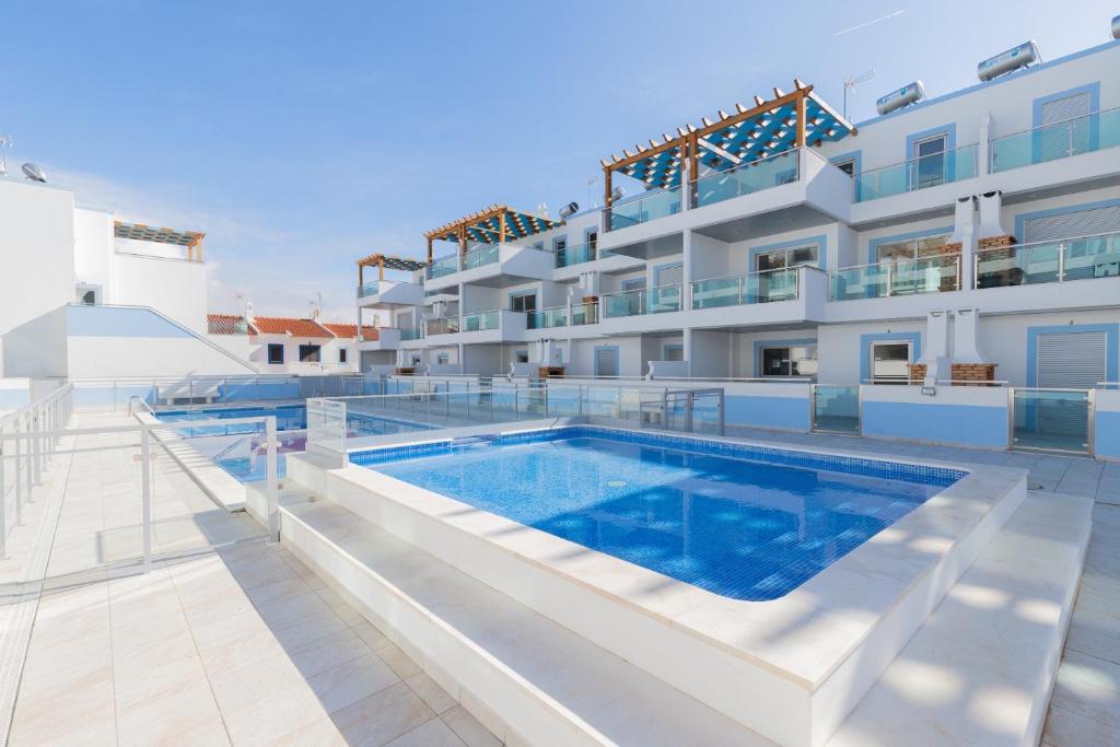 a swimming pool in front of a building at Numar S by ALGARVEMANTA in Manta Rota