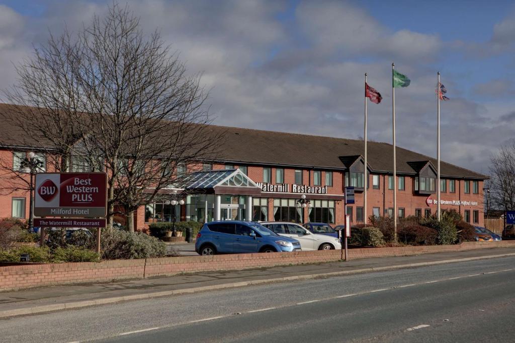 a building with two flags on the side of a street at Best Western Plus Milford Hotel in South Milford