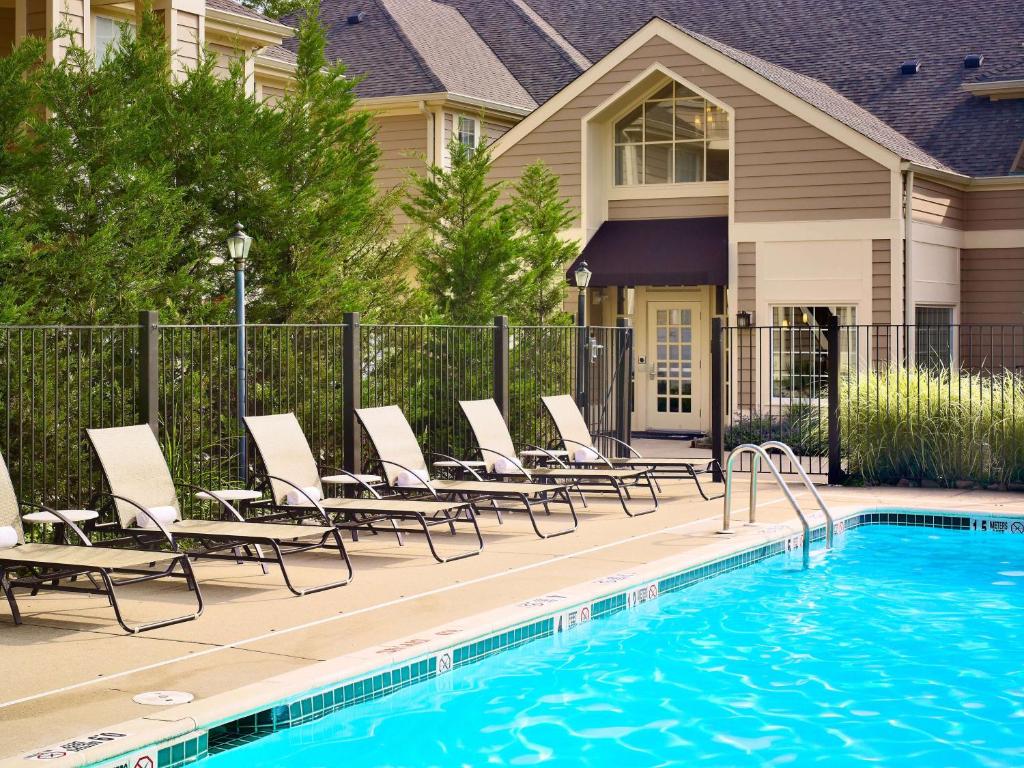 a swimming pool with lounge chairs next to a house at Sonesta ES Suites Princeton in Princeton