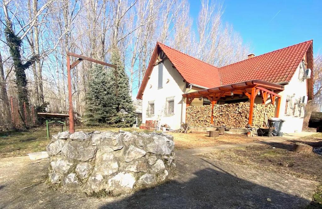 ein weißes Haus mit einem roten Dach und einer Steinmauer in der Unterkunft Harcsáztat-Lak in Tiszaderzs