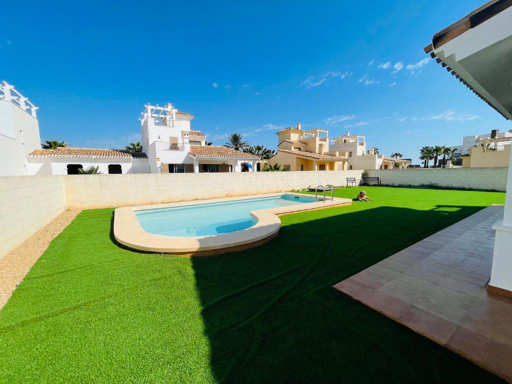 un cortile con un prato verde e una piscina di Villa A70 by Alina365 a La Manga del Mar Menor