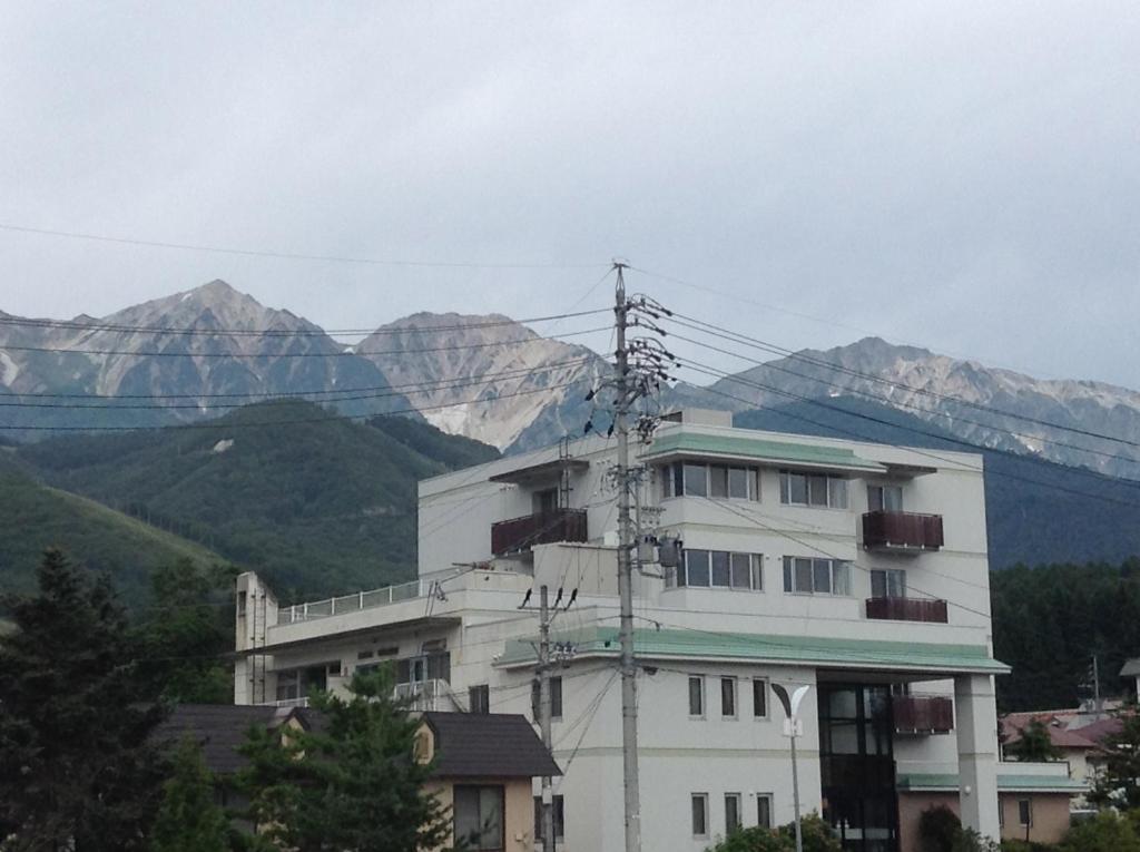 ein weißes Gebäude mit Bergen im Hintergrund in der Unterkunft Happokan in Hakuba