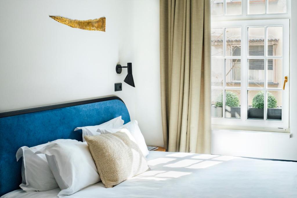 una camera da letto con letto con testiera blu e finestra di Pavilion Hotel & Social Club a Belgrado