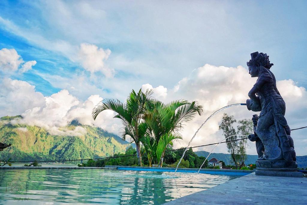 a statue of a boy with a fountain in a pool at Mapa Lake View Bungalow in Kintamani