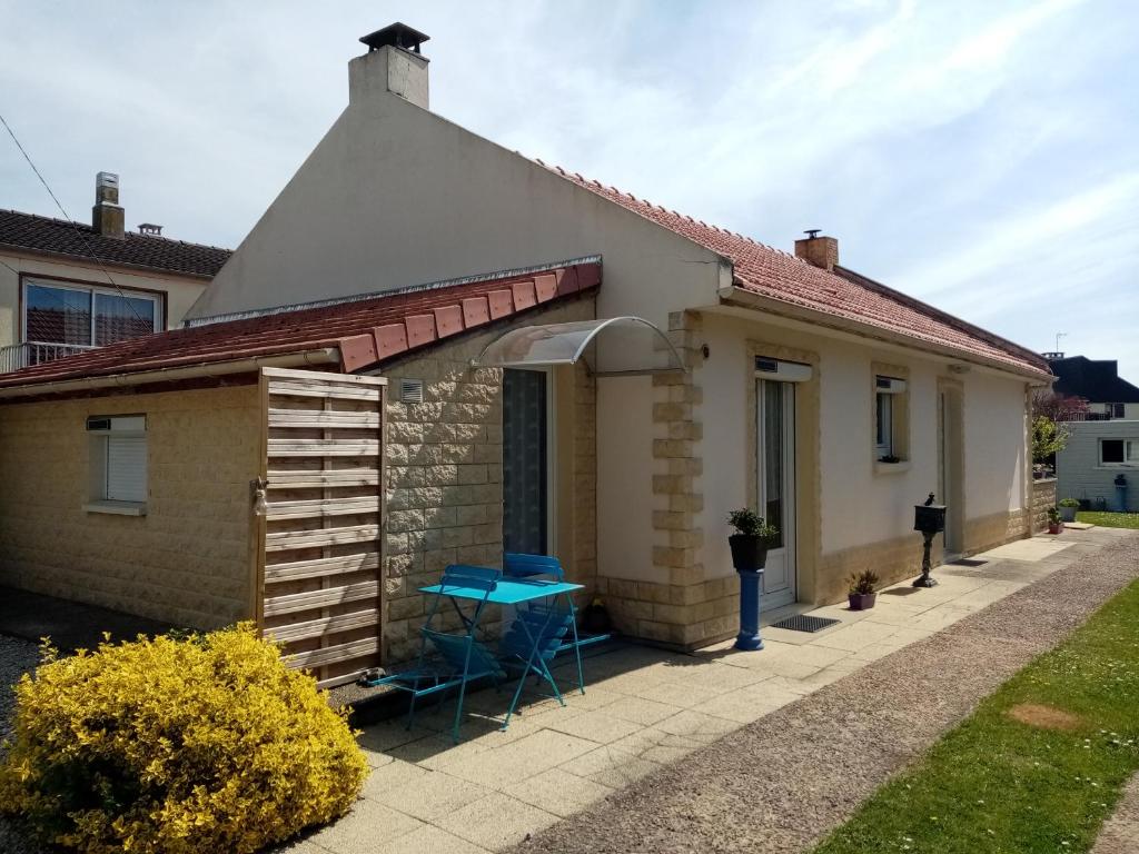 een klein huis met een blauwe tafel ervoor bij Chez Gigi in Merville-Franceville-Plage