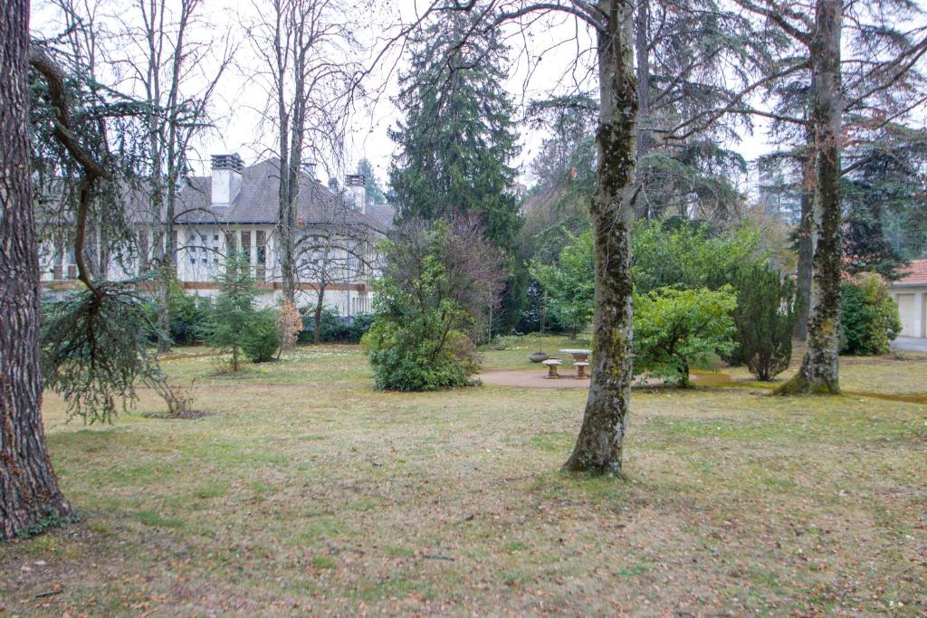 un parc avec des arbres et un banc devant une maison dans l'établissement Le Parc, à Thonon-les-Bains