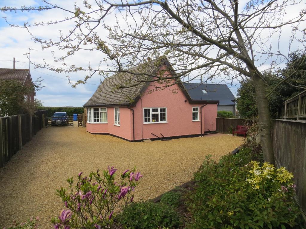 a pink house in a yard with a driveway at 44 Sea Lane in Hunstanton