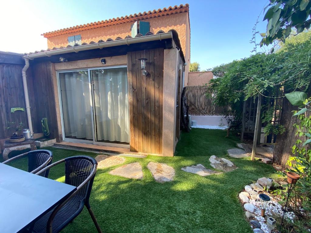 a garden with a wooden shed with a table and chairs at Agréable studio proche StTropez Piscine et Tennis in Gassin