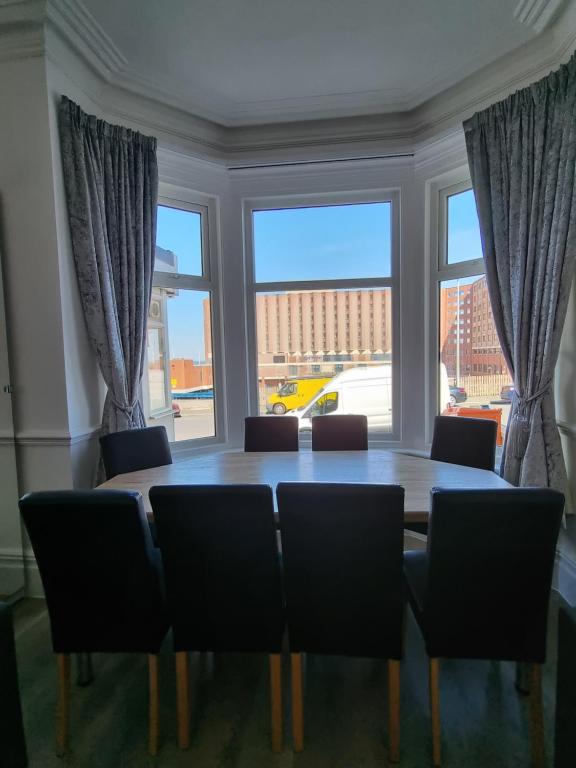 a dining room table with chairs and a large window at Granada Apartments Derby Road in Blackpool