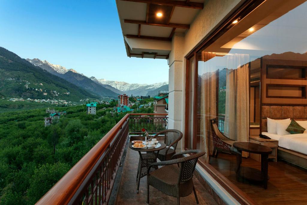 a balcony with a bed and a table and chairs at The Orchid Manali - a Boutique Hotel in Manāli