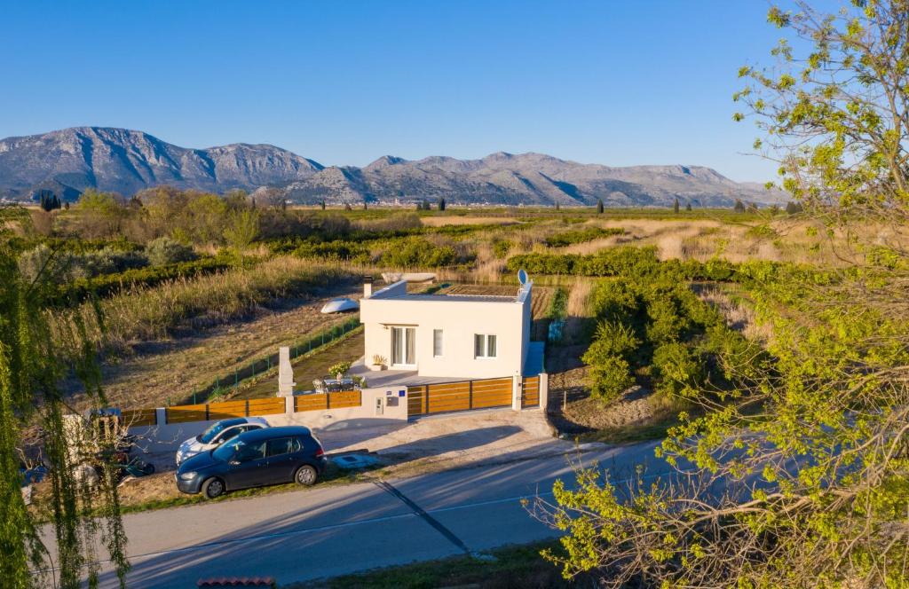 ein kleines weißes Haus auf einem Feld mit Bergen im Hintergrund in der Unterkunft Rest House ZEN in Opuzen