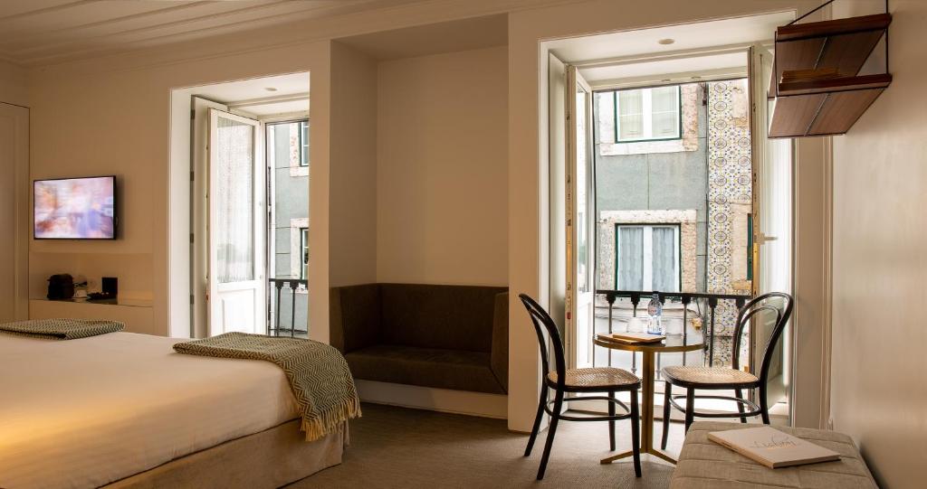 A bright room with a double bed, sofa, dining table and street-facing windows.