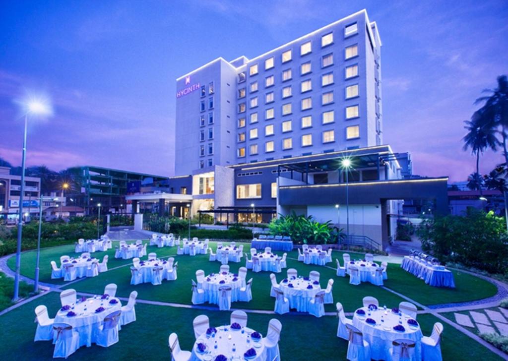 una stanza con tavoli e sedie bianchi di fronte a un edificio di HYCINTH Hotels a Trivandrum