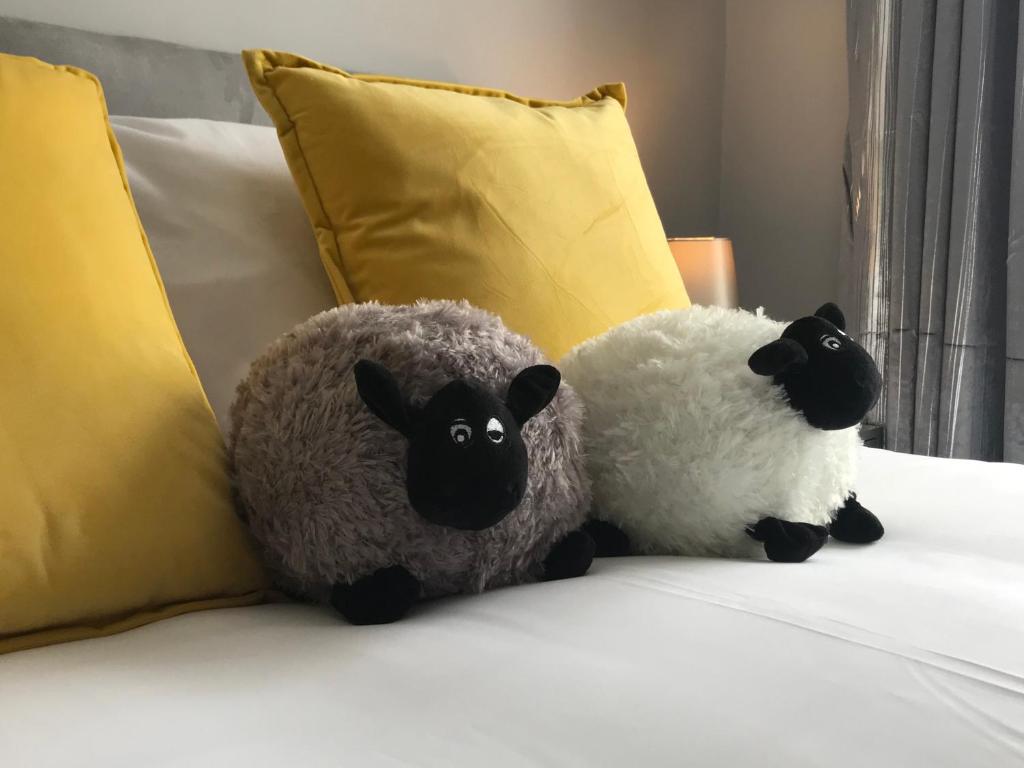dos ovejas de peluche sentadas encima de una cama en Inn Cardiff en Cardiff