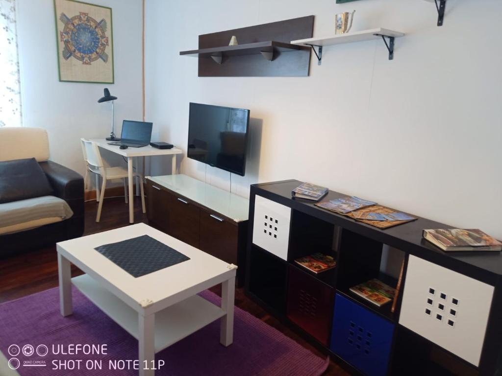 a living room with a tv and a desk with a table at Apartamento Portugalete in Portugalete