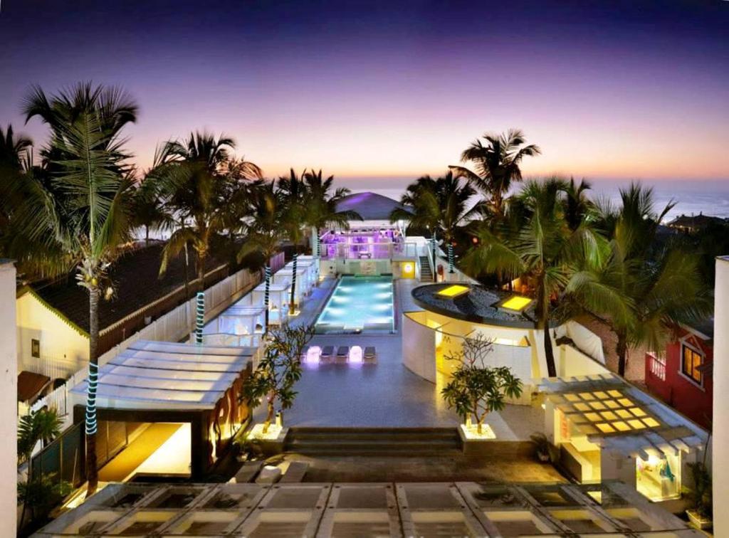 un resort con piscina e palme di notte di The Park Calangute Goa a Calangute
