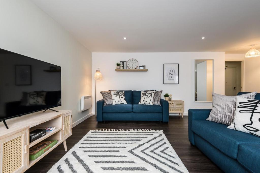 a living room with a blue couch and a tv at Host & Stay - The Scandi Hideaway in Liverpool