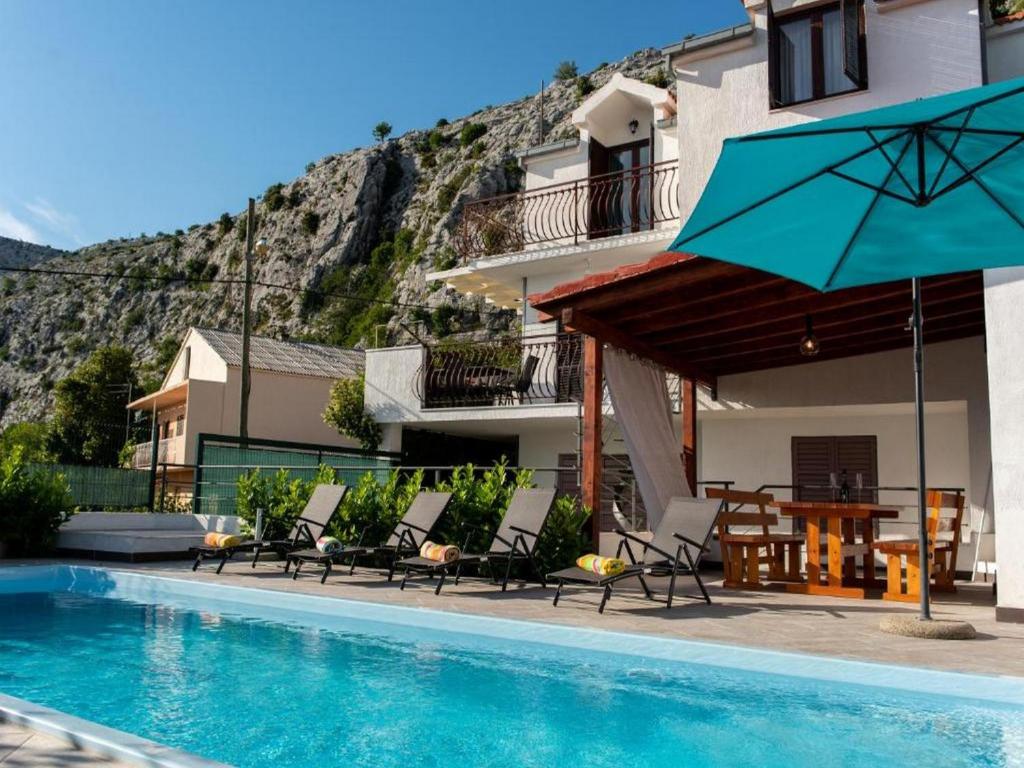 uma piscina com cadeiras e um guarda-sol ao lado de um edifício em Holiday home Mons Aureus em Gornje Sitno