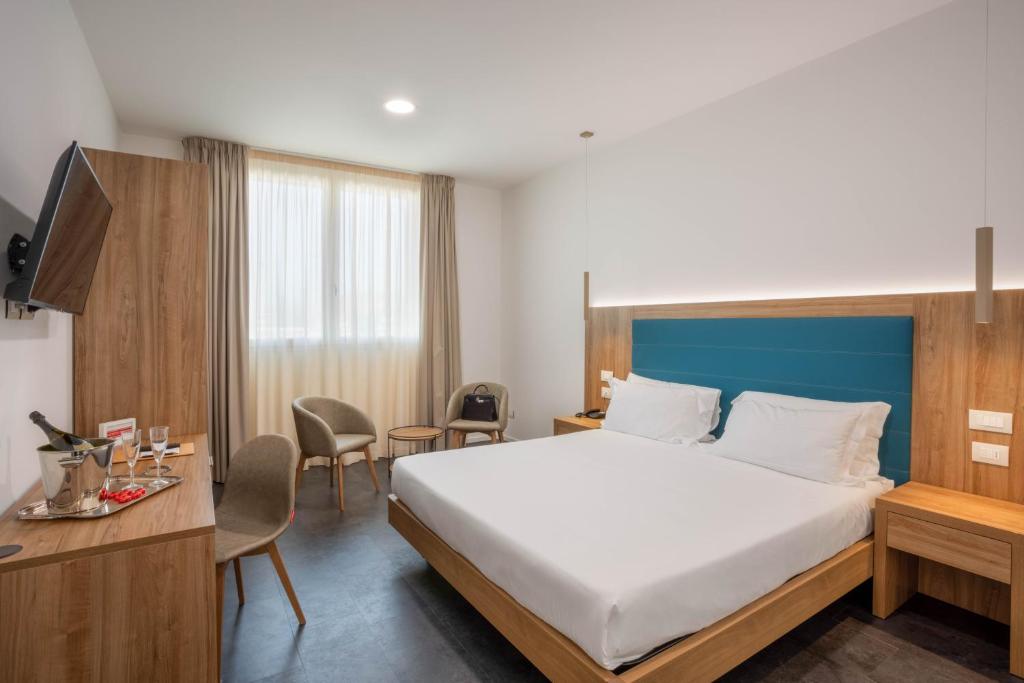 ein Hotelzimmer mit einem großen Bett und einem Schreibtisch in der Unterkunft V Hotel in Ancona