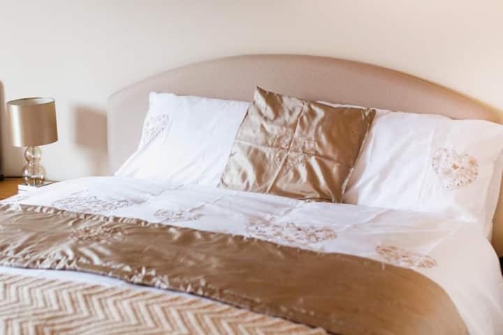 a bed with white sheets and brown and white pillows at Portora House in Silverhill