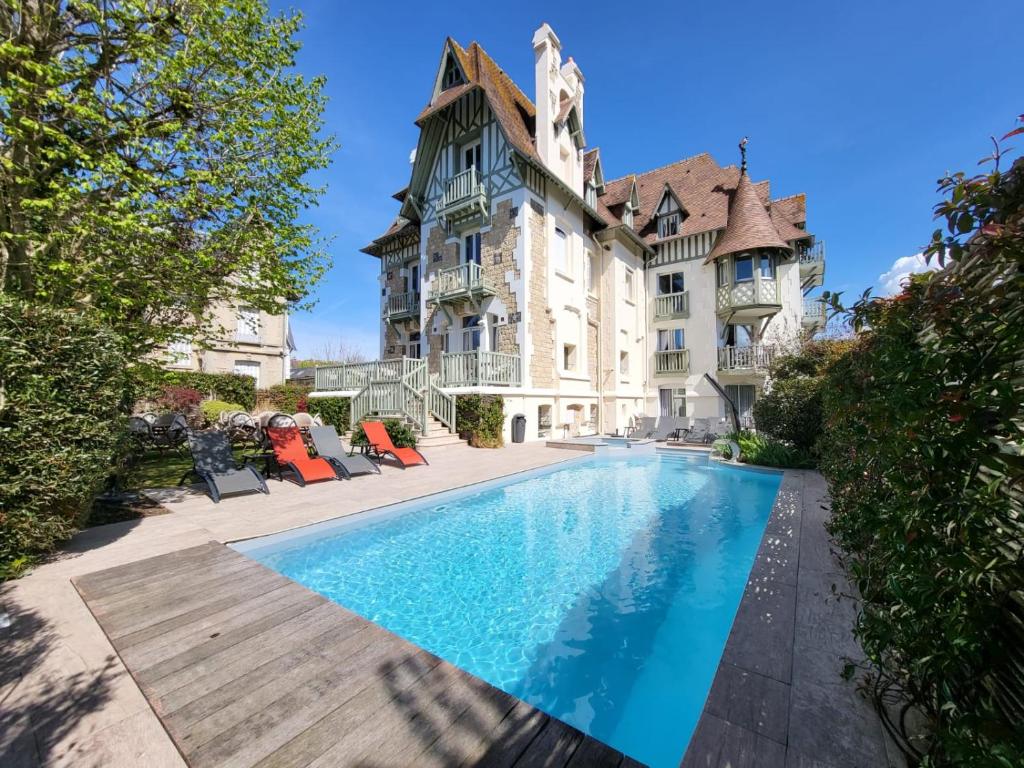 un domaine avec une piscine en face d'un bâtiment dans l'établissement Villa Augeval Hôtel de charme & Spa, à Deauville