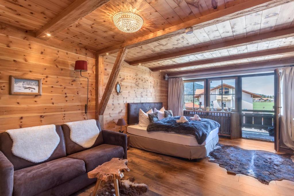 sypialnia z łóżkiem, kanapą i oknem w obiekcie Alpenauszeit im Zirbenholz Chalet w mieście Inzell