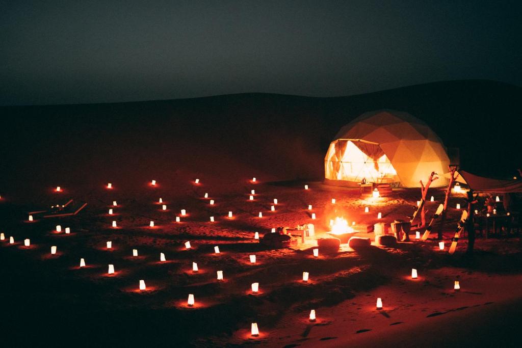 um grande grupo de velas em um campo à noite em Desert Luxury Camp em Merzouga