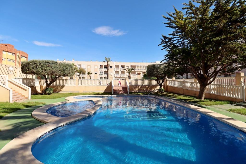 una gran piscina azul en un patio con árboles en Apartment Azul, en Torrevieja