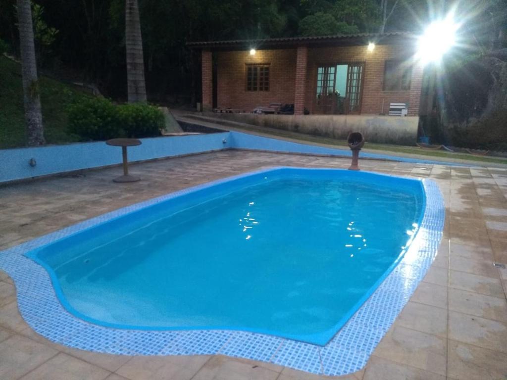 a blue swimming pool in a yard at night at Chácara Felicidade Um pedacinho do Céu in Mairiporã