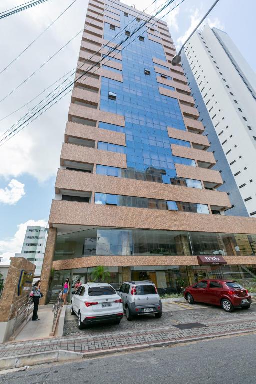 a tall building with cars parked in front of it at Manaíra Apart Flat in João Pessoa