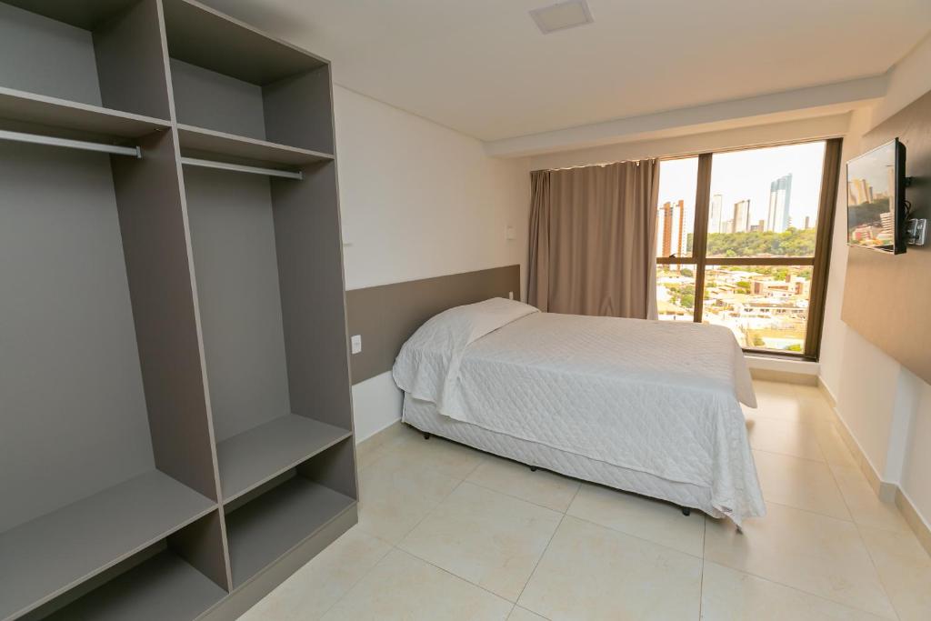 a bedroom with a bed and a large window at Manaíra Apart Flat in João Pessoa