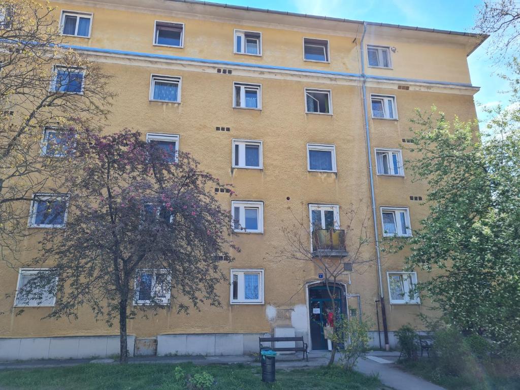 duży żółty budynek z białymi oknami i drzewem w obiekcie Tatabánya Újvárosi lakás w mieście Tatabánya