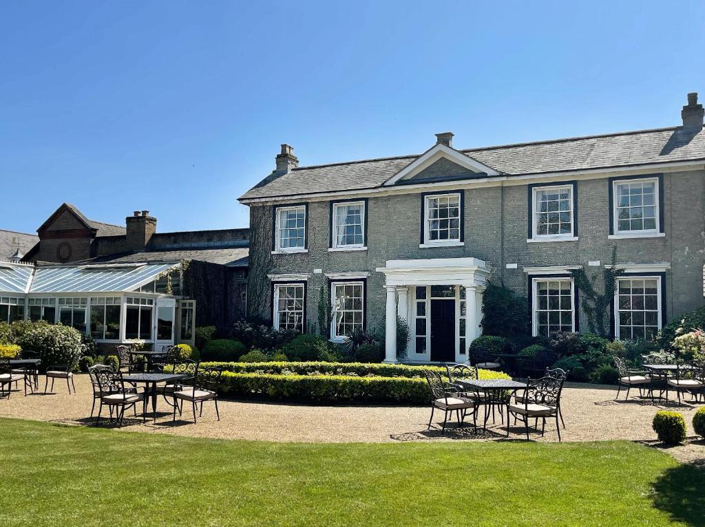 a large house with tables and chairs in front of it at Park Farm Hotel in Norwich