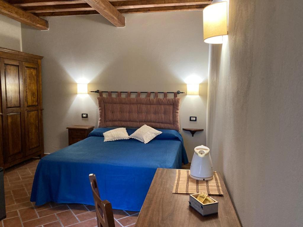 1 dormitorio con cama azul y mesa de madera en Agriturismo La Vecchia Quercia, en Montemerano