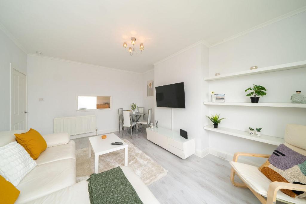 a white living room with a white couch and a tv at Sidlaw View in Dundee