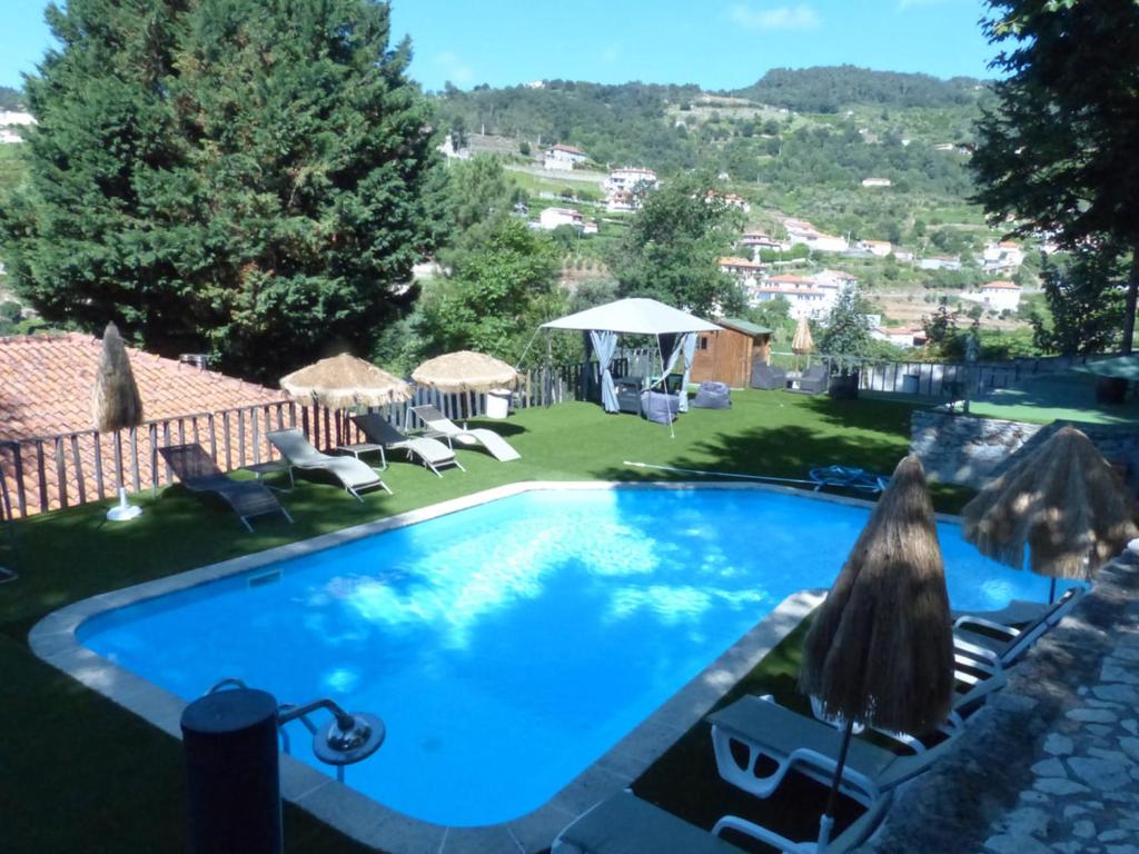 uma piscina num quintal com cadeiras e guarda-sóis em Quinta da Cartida em Santa Marinha do Zêzere