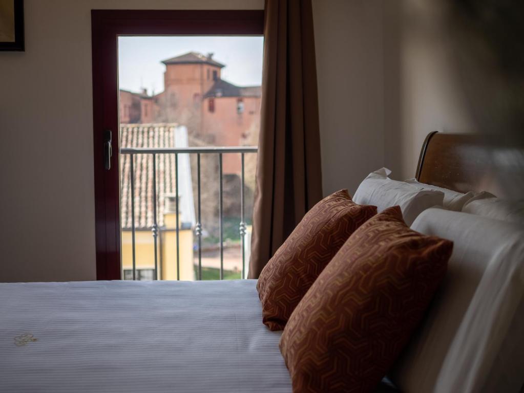 una camera da letto con letto con cuscini e balcone di Ego' Residence Ferrara a Ferrara