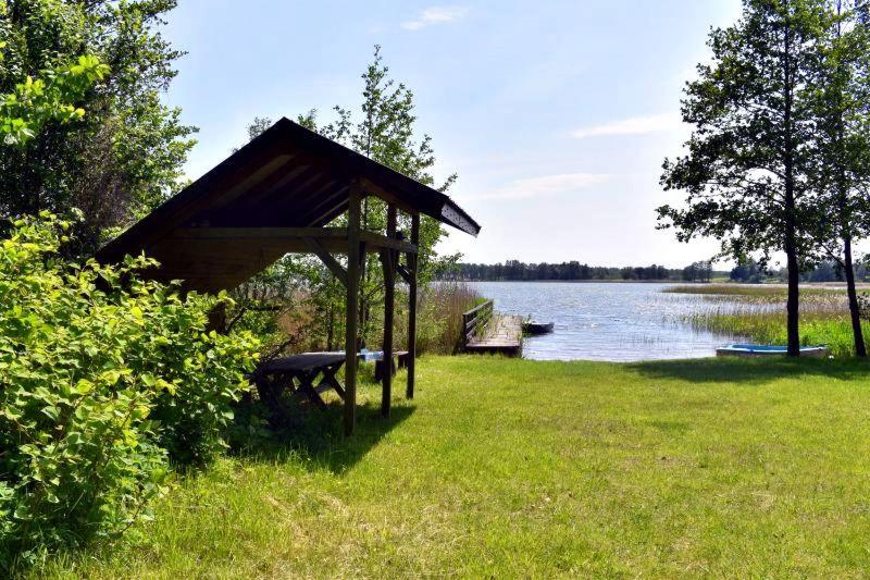 a gazebo in the grass next to a lake at Agroturystyka u Oli in Smolany Dąb