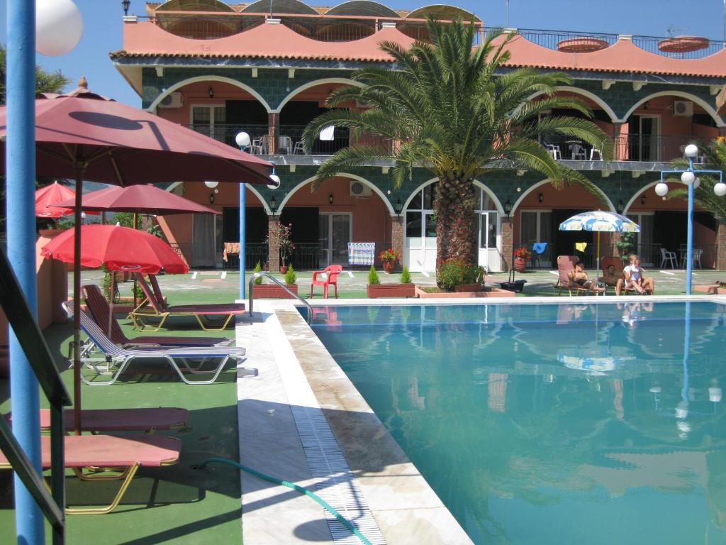 a swimming pool with chairs and umbrellas next to a building at Villa Magdalena studios in Ágios Ioánnis