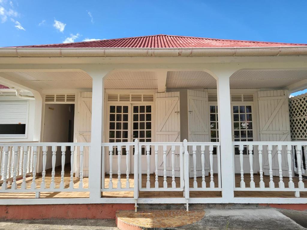 a white porch on a house with a white fence at Villa Majorelia in Vieux-Habitants