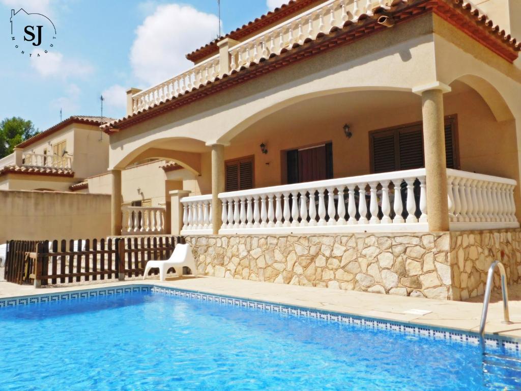 una villa con piscina di fronte a una casa di Chalet con piscina (B) a Les tres Cales