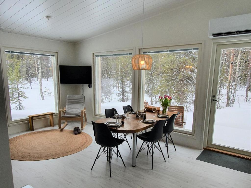 a dining room with a table and chairs and windows at Ylläs Terhakka - Uusi huvila kuudelle in Äkäslompolo