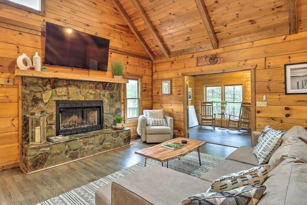 sala de estar con chimenea de piedra y TV en Blue Ridge Cabin with Hot Tub, Fire Pit, and Game Room, en Cherry Log